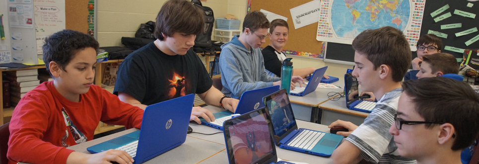 Male students working on laptops in a classroom