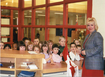 Adult female principal with Kindergarten students in school
