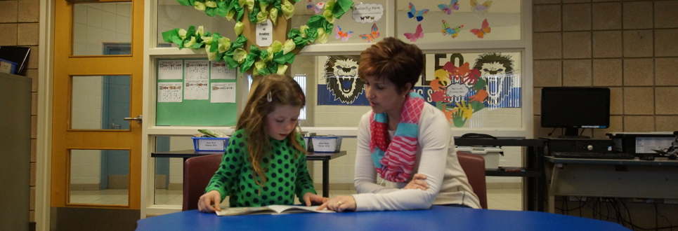Parent volunteer reading with student